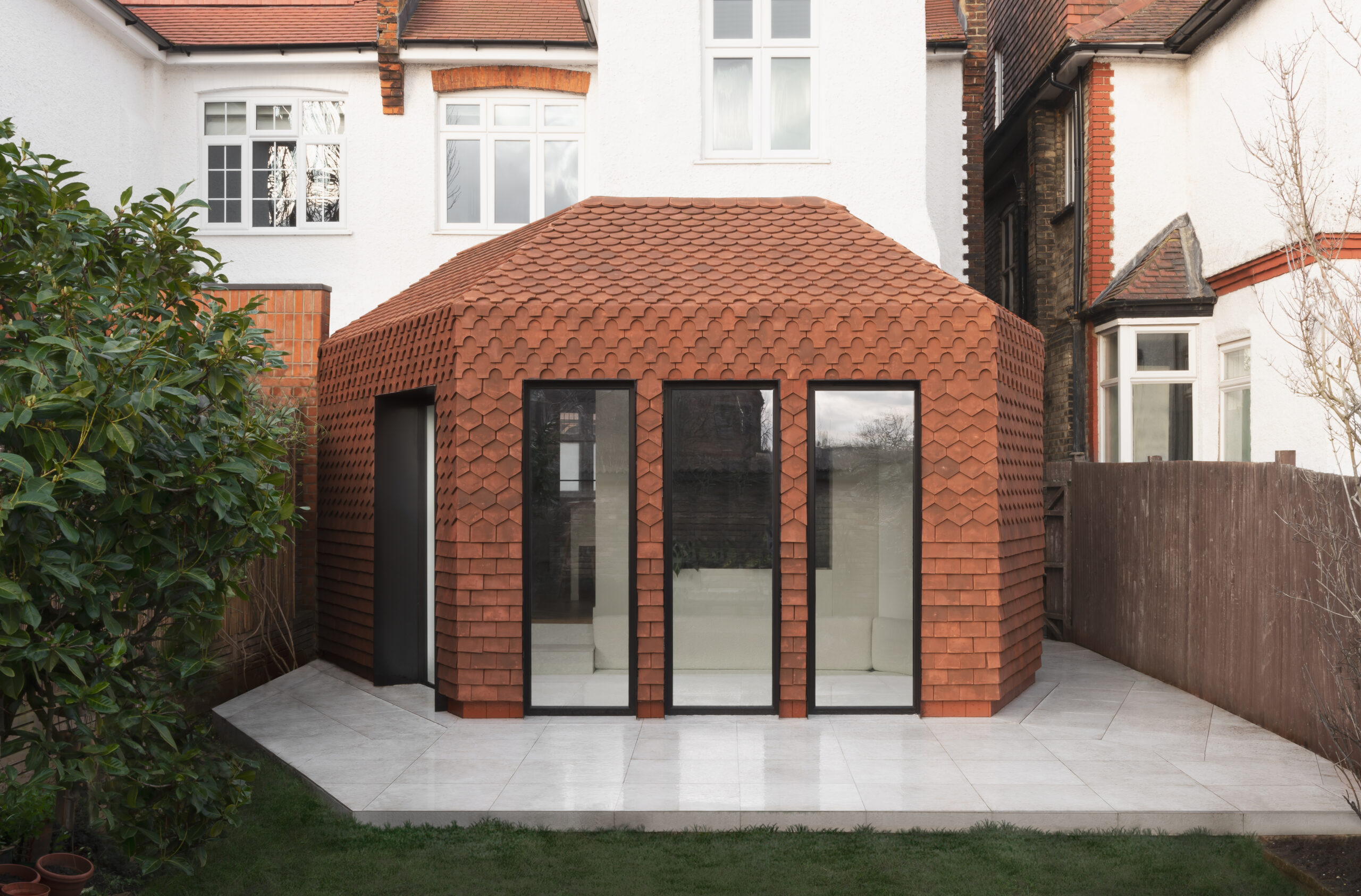 Contemporary style extension with red clay tiles on the facade